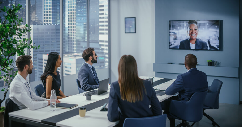Corporate employees in board room watching presenter on TV