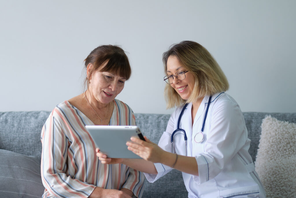 Female doctor showing results of peripheral arterial disease test at home to female patient