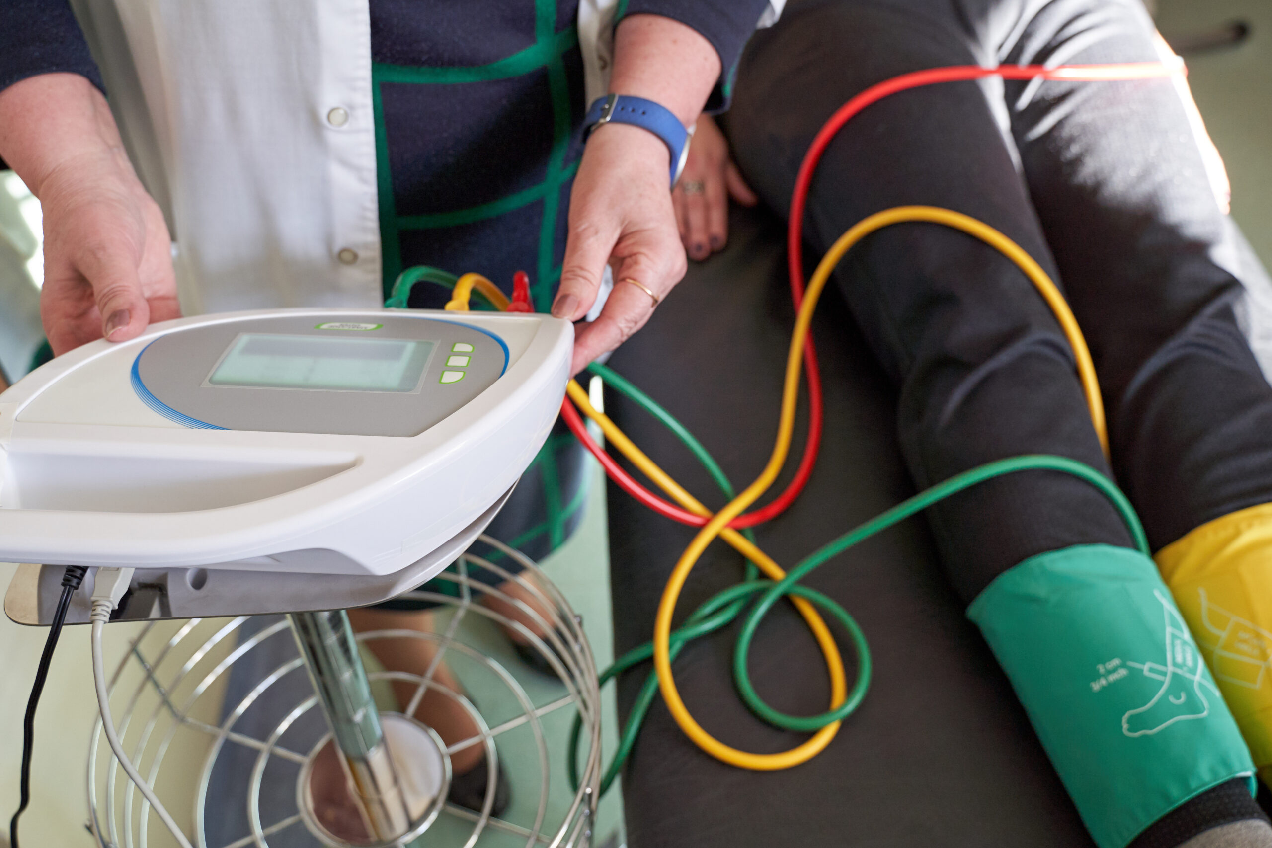 Patient lying on exam table receiving ankle-brachial index (ABI) test